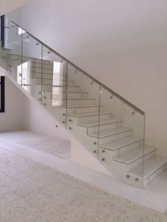 a white staircase with glass railing and handrail