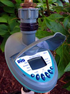 an electronic device is attached to a pole in front of some trees and bushes with green leaves