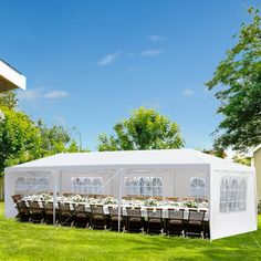 a large white tent set up with tables and chairs for an outdoor wedding or party