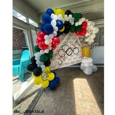 an arch made out of balloons with the olympic rings on it in front of a patio