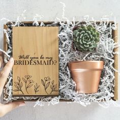 someone is holding a box with some plants in it and the words will you be my bridesmaid?