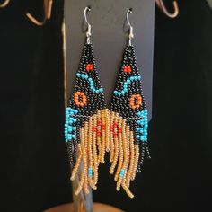 a pair of beaded earrings with an animal face on it's ear ends