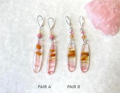 These long pink and gold boho earrings are perfect for spring and summer, and the contrast between pastel pink and bold gold are striking.   The colors give these a slight funky, retro look, while at the same time being elegant in color and shape. Cherry Quartz is a man made stone created using natural reconstituted quartz and cinnabar. It's then melted and given its dazzling energetic flashes or pink color in the clear quartz. The cinnabar in the Cherry-Quartz creates cloud formations, vortex, feathers, and striations, adding to the beauty of this stone.It creates a transparent, stone with streaks and wisps of pink, gold, and white of varying intensity. Due to the transparency, they will look completely different depending on the lighting and the color behind them (like your hair), as you Bohemian Teardrop Pink Earrings, Pink Teardrop Bohemian Jewelry, Bohemian Long Drop Earrings For Summer, Bohemian Pink Teardrop Jewelry, Pink Teardrop Earrings For Festival, Pink Teardrop Festival Earrings, Pink Teardrop Jewelry For Festivals, Pink Bohemian Jewelry With Ear Wire, Bohemian Pink Jewelry With Ear Wire