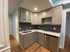 an empty kitchen with gray cabinets and white counter tops is pictured in this image from the doorway