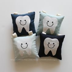 three pillows with tooth shapes on them are sitting next to each other, one has a smiling face