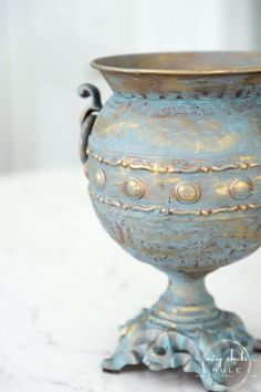 a metal vase sitting on top of a white table