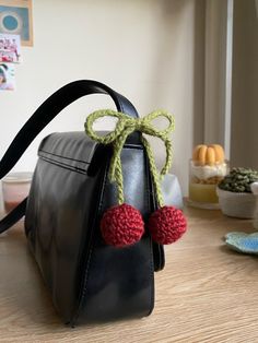 a black purse with two pom - poms attached to it