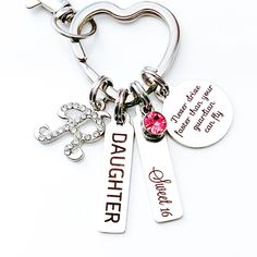 a heart shaped keychain with two charms and a name tag attached to it