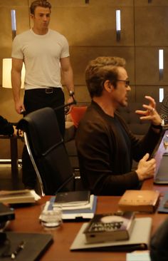 a group of people sitting around a table with laptops