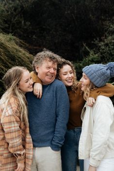 a group of people standing next to each other in front of some trees and bushes