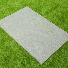 a square concrete slab laying on top of green grass