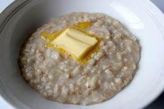 a white bowl filled with oatmeal and butter on top of a table