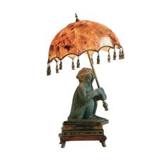 a lamp that is sitting on top of a wooden stand with a monkey holding an umbrella