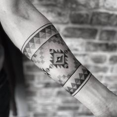 a man's arm with tattoos on it and a geometric design in the middle