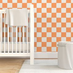 a white crib next to a wall with orange and white checkered tiles on it