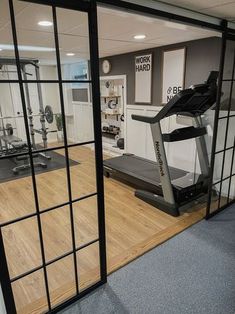 an empty gym with treadmills and exercise equipment in the foreground, through glass doors