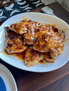 a white plate topped with chicken covered in gravy on top of a wooden table