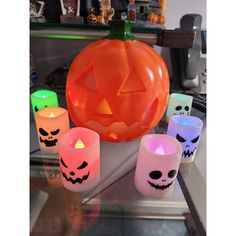 lighted candles with halloween faces on them sitting in front of a pumpkin