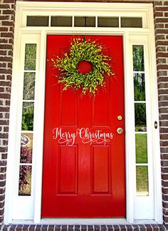 a red front door with a wreath on the top and merry christmas written on it