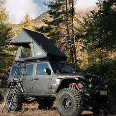 a jeep with a tent on top parked in the woods