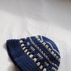 a blue crocheted hat laying on top of a white sheet