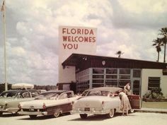 several classic cars parked in front of a building with a sign that says florida welcomes you