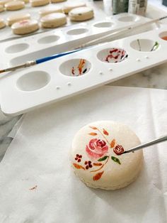 a person is painting flowers on some cookies