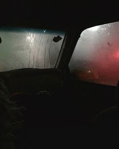 two people sitting in the back seat of a car at night, looking out the window