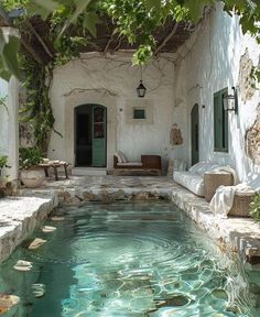 an outdoor swimming pool surrounded by greenery and stone steps with doors leading to it