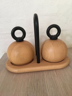 two wooden teapots with black handles on a wood tray