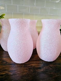 three pink vases sitting on top of a wooden table