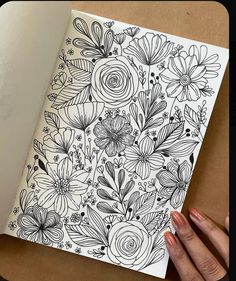 a hand holding an open notebook with flowers on it