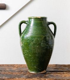 a green vase sitting on top of a wooden table