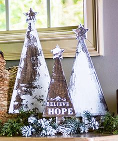 three wooden christmas trees sitting on top of a mantle