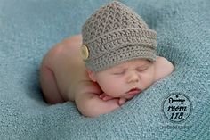 a newborn baby wearing a crochet hat sleeping on a blue blanket with its eyes closed