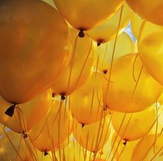 many yellow balloons are floating in the air