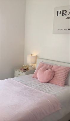 a white bed with pink pillows in a bedroom next to a wall mounted sign that reads prahe mill road