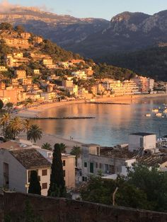 the town is next to the water with boats on it and mountains in the background