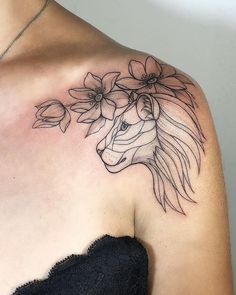 a woman's shoulder with a tattoo of a lion and flowers on her chest