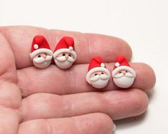 three tiny santa claus faces are in the palm of someone's hand, wearing red and white hats