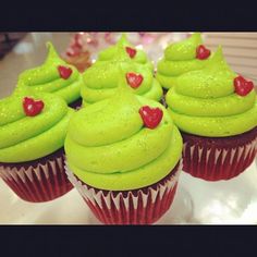 cupcakes with green frosting and red hearts on them sitting on a plate