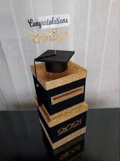 a graduation cake that is decorated with gold and black glitters, topped with a graduate's cap