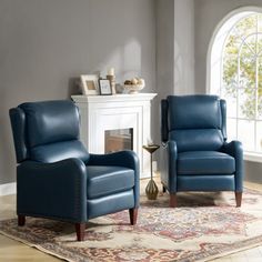 a living room with two blue chairs and a rug in front of a fireplace area