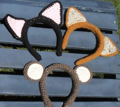 three crocheted hats with ears and tails on top of a blue park bench