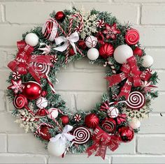 a christmas wreath on a brick wall with candy canes and ornaments hanging from it