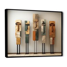 four wooden sculptures are lined up against a wall