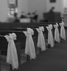 rows of pews with white bows tied to them in a church aisle lined with pews