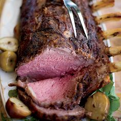 a large piece of meat is on a plate with potatoes and garnishes