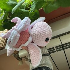 a person holding a stuffed animal in front of a potted plant