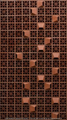 an intricately designed wall made out of brown bricks and metal grates, with geometric designs on the sides